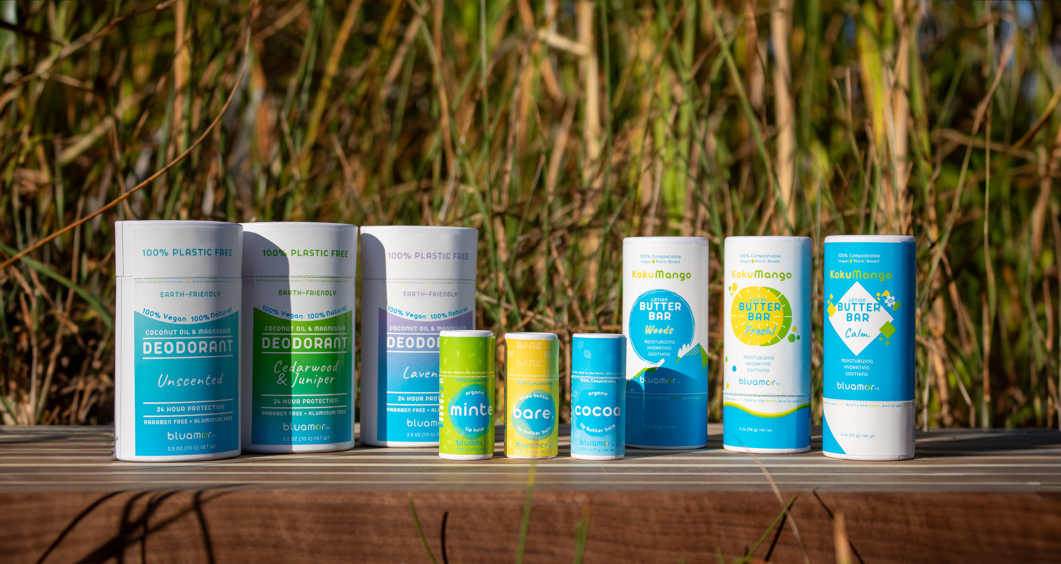 A range of eco-friendly, plastic-free personal care products displayed outdoors, featuring deodorants and lip balms in colorful containers.
