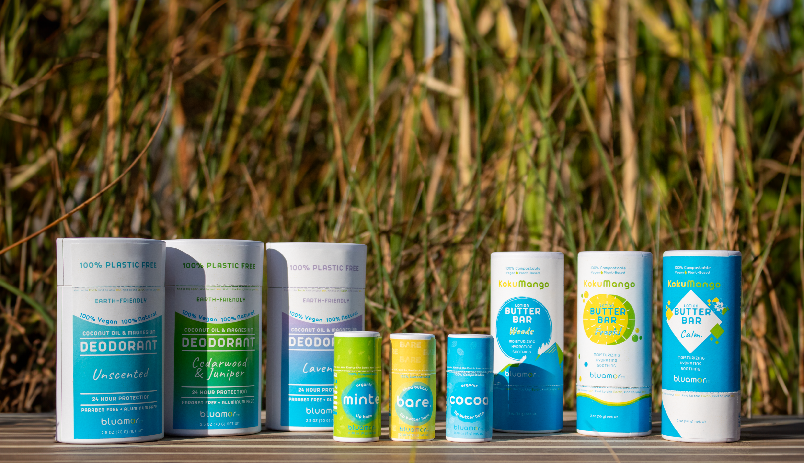 A range of eco-friendly, plastic-free personal care products displayed outdoors, featuring deodorants and lip balms in colorful containers.