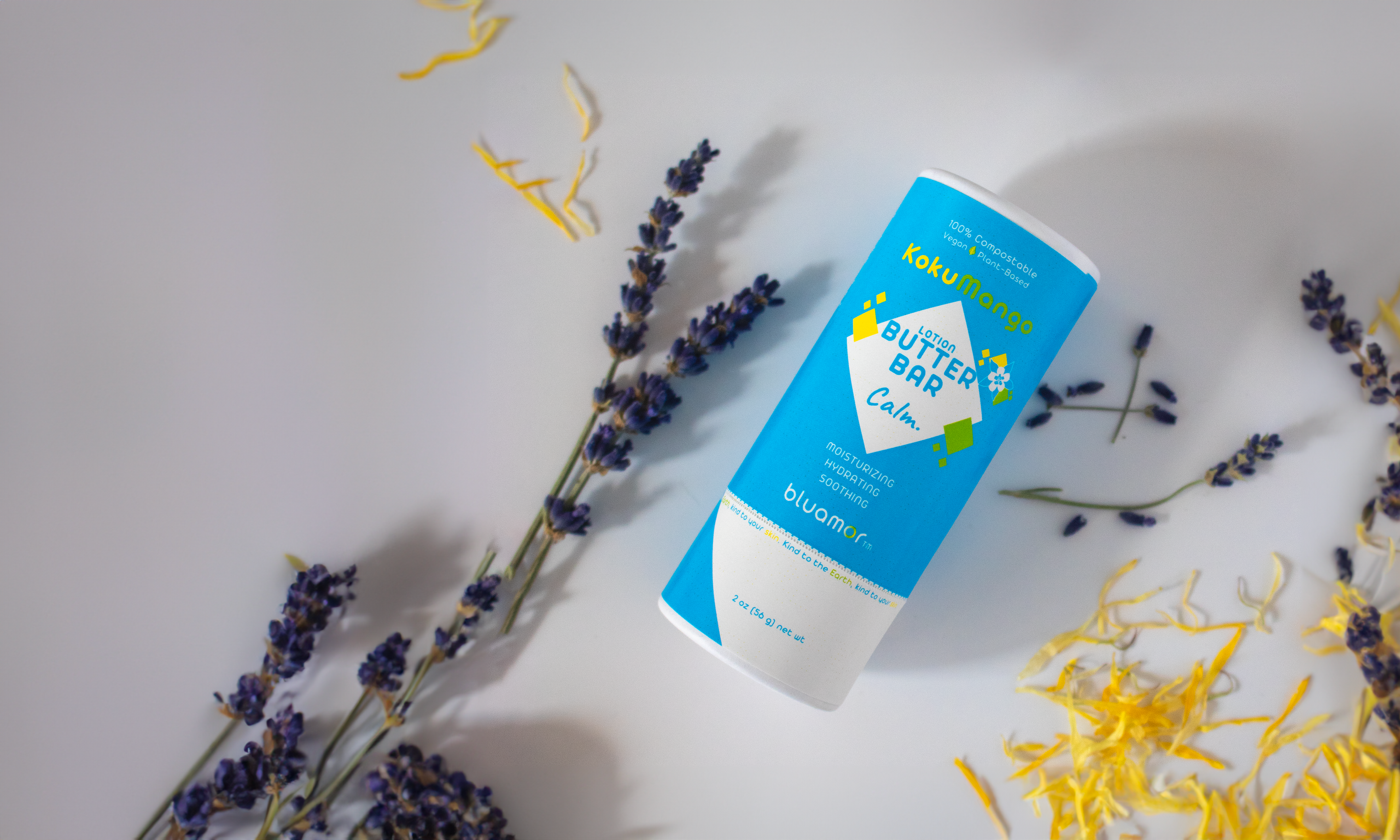 A blue lotion butter bar labeled "Calm" by bluamor, surrounded by lavender and yellow floral accents on a light background.